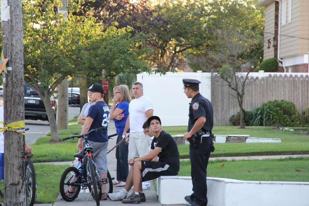 A policeman speaks to area residents who were horrified to see a man get hit while riding his bike.