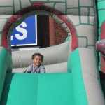 Isaiah Diaz, 3, of Ridgewood, peeks over the edge of one of a number of inflatable slides at the festivities.