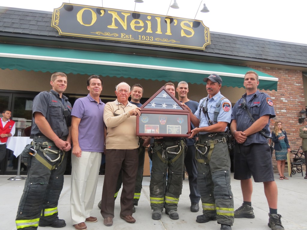 O'Neill's owners George O'Neill, third from left, and Danny Pyle, second from left, celebrate the reopening of their beloved restaurant and bar in Maspeth alongside members of Rescue 4. The firefighters presented the O'Neill family with an American flag they saved while battling the blaze that destroyed O'Neill's in 2011. Anna Gustafson/The Forum Newsgroup 