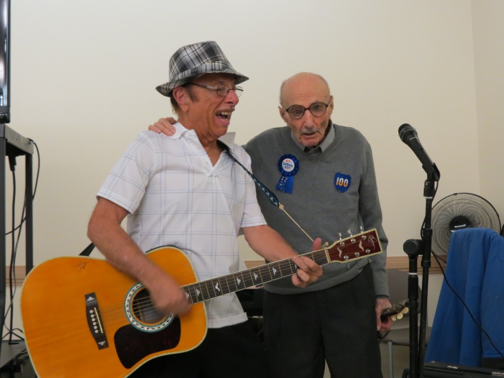 Howard Beach Senior Center member Jimmy DiNapoli plays the guitar while Max Stern sings.