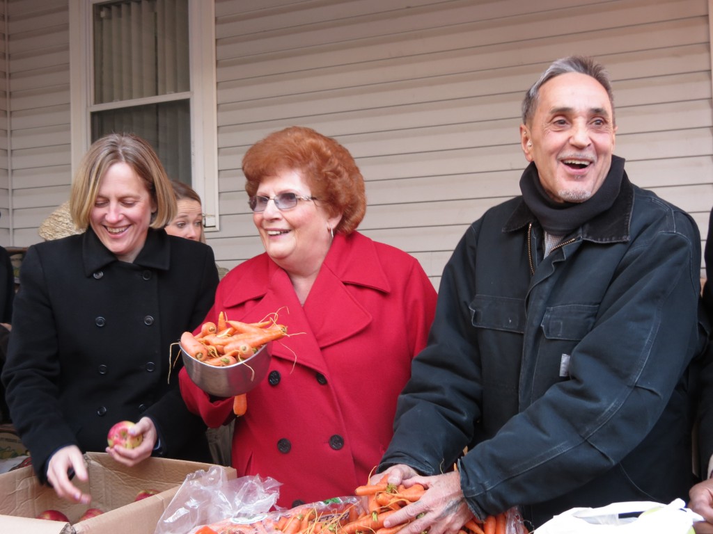 Borough President-elect Melinda Katz, Councilwoman Karen Koslowitz, and River Fund Executive Director Swami Durga Das hand out fresh vegetables to residents lining up at the Richmond Hill food pantry on Saturday.