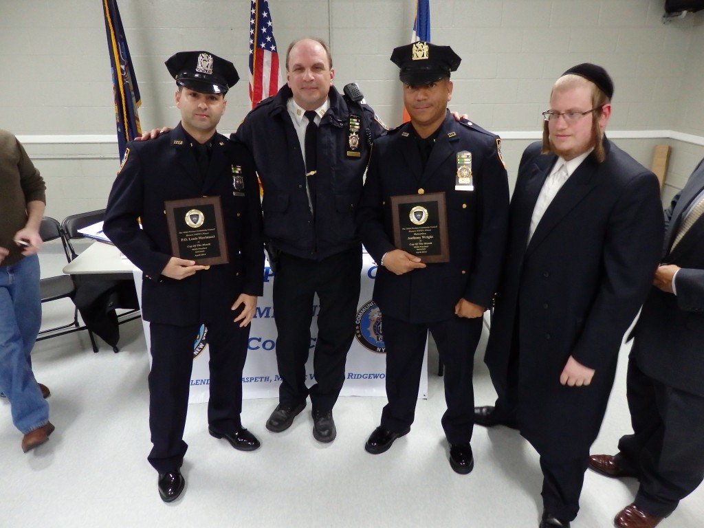 Capt. Christopher Manson, center, and Community Council Vice President Abraham Markowitz, right, honor Officer Louis Marinacci, left, and Detective Anthony Wright, second from right, for a major narcotics bust.  Photos by Phil Corso