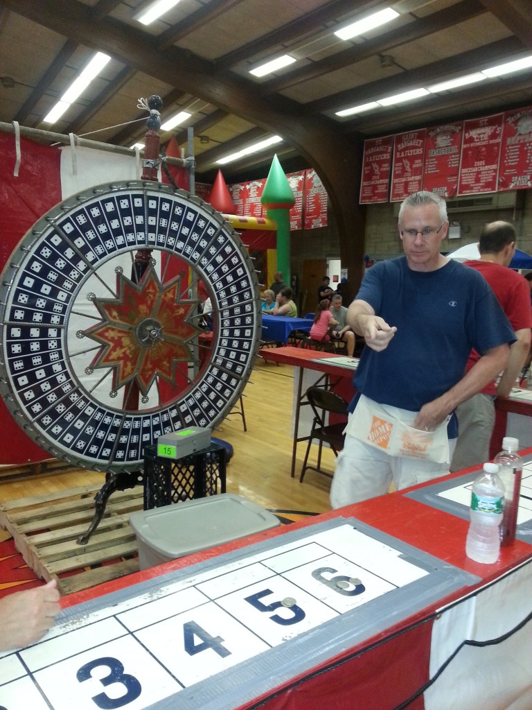 Volunteer Bill Kellher spins the 'Dice Wheel."   Photo by Debbie Cohen