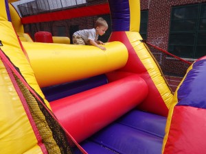 A youngster barrels through the inflatable obstacle course at last Thursdays' community event. Photo by Phil Corso