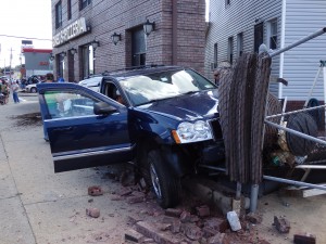 A car sits vacant after slamming into the fence in front of Romeo's Pizzeria in Ozone Park.   Photo by Phil Corso